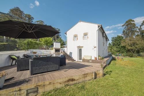 a white house with an umbrella on a deck at Casa do Porto Carreiro in Oliveira de Azemeis