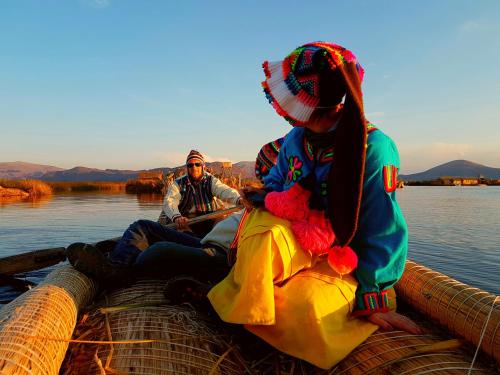 two people sitting on the back of a boat on the water at Uros Lake Titicaca Lodge in Puno