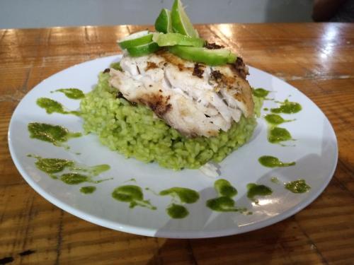 a white plate with a piece of chicken and green peas at Riviera Punta Cana Eco Travelers in Punta Cana