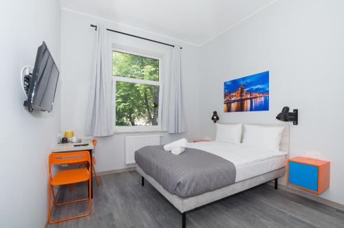 1 dormitorio con 1 cama, TV y ventana en Zefiro Stajenna, en Gdansk