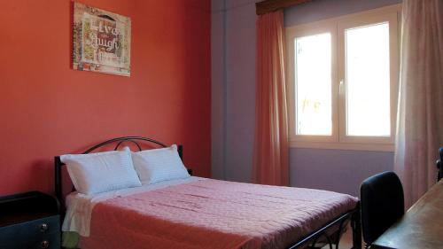 um quarto vermelho com uma cama e uma janela em Lakones View House em Lákones