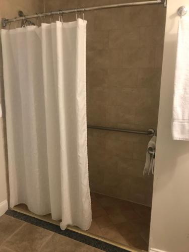 ウォルサムにあるCrescent Suites Hotelのバスルーム(白いシャワーカーテン付きのシャワー付)が備わります。