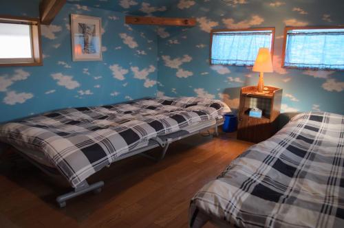 Spr Guesthouse في شيراهاما: سريرين في غرفة ذات جدران زرقاء مع سحب
