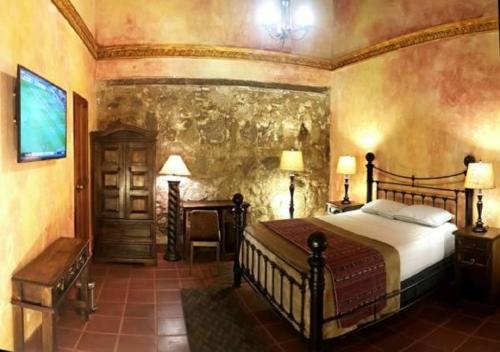 a bedroom with a bed and a stone wall at Hotel Eterna Primavera Antigua in Antigua Guatemala