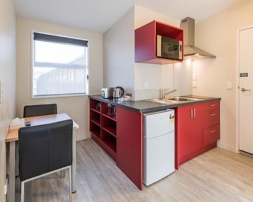 a kitchen with red cabinets and a white refrigerator at C-Motel in Christchurch