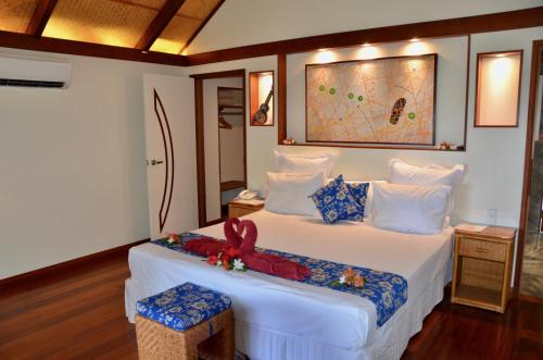 a bedroom with a white bed with a red bow on it at Tamanu Beach in Arutanga