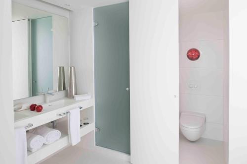 a white bathroom with a toilet and a mirror at Barceló Sants in Barcelona