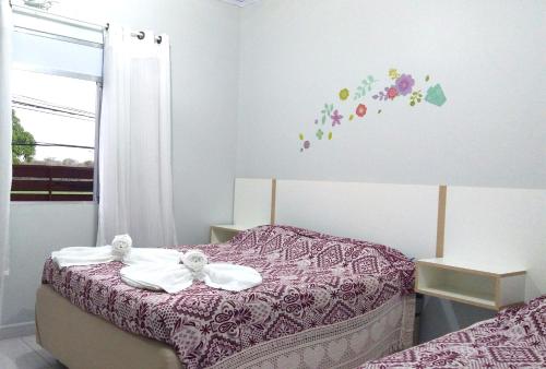 um quarto com uma cama com flores na parede em Hotel Itamiaru em Iguape