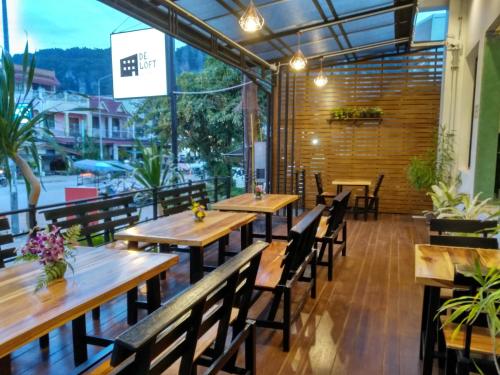 un restaurante con mesas y sillas de madera y una gran ventana en De Loft Hotel en Ao Nang Beach