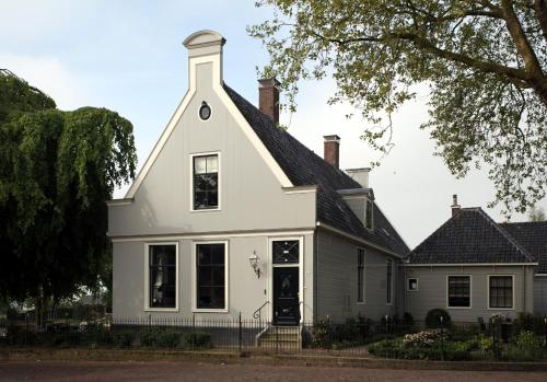 a white house with a black roof at Inn on the Lake in Broek in Waterland