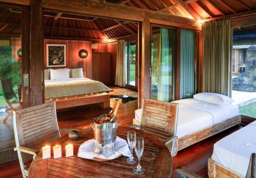 a bedroom with a bed and a table and chairs at Bali Luxury Boutique Resort and SPA in Tanah Lot