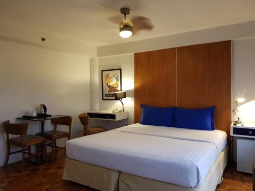 Schlafzimmer mit einem Bett mit blauen Kissen und einem Schreibtisch in der Unterkunft The Clipper House in Manila