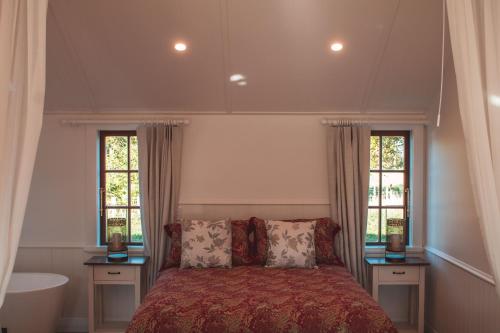 a bedroom with a bed and two windows and a tub at Woodside Orchard in Greytown