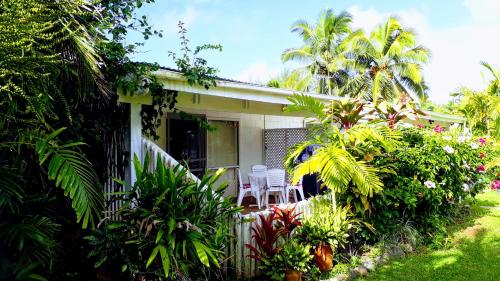 a house with chairs and plants in front of it at Herons Reef Holiday Apartments in Rarotonga