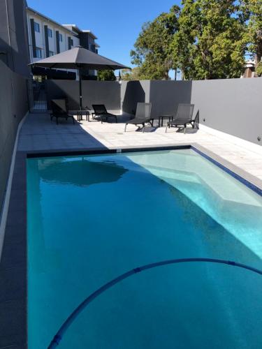 a blue swimming pool with chairs and a umbrella at Best Western Plus North Lakes Hotel in North Lakes
