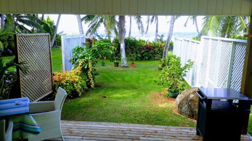 a patio with a yard with a table and a view of the ocean at Herons Reef Holiday Apartments in Rarotonga