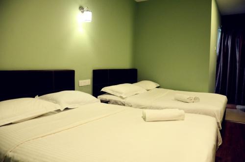 2 łóżka w pokoju z zielonymi ścianami w obiekcie Hotel Sri Rembia w Malakce