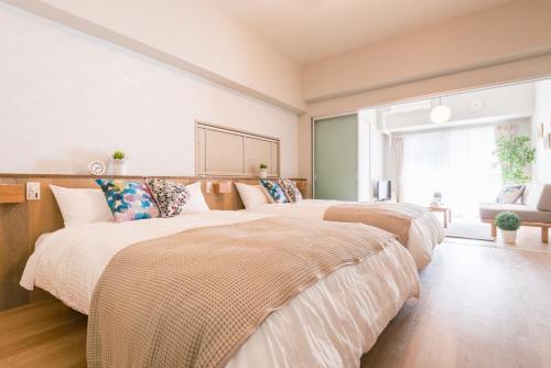 a bedroom with two beds and a couch at nedoco OSAKA SHINSAIBASHI - formerly FORESTAY Shinsaibashi in Osaka