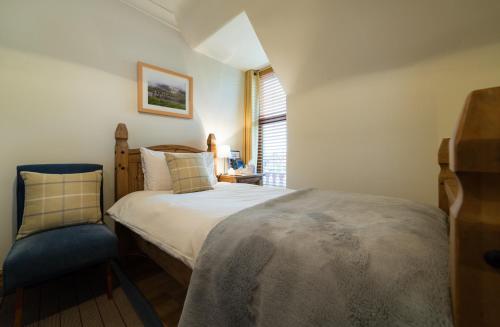 a small bedroom with a bed and a chair at Kylelachin in Dingwall