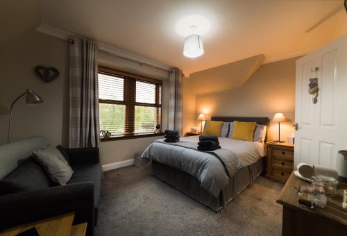 a bedroom with a bed and a couch and a window at Kylelachin in Dingwall
