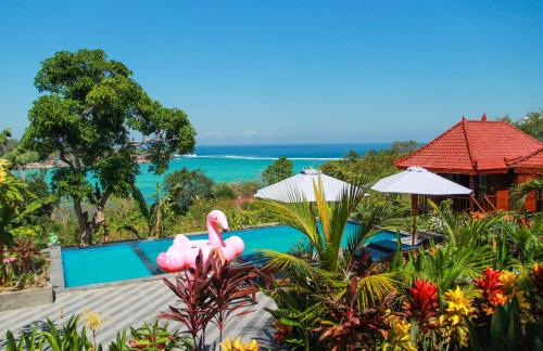 a resort with a swimming pool and pink flamingos at Bukit Permata Lembongan in Nusa Lembongan