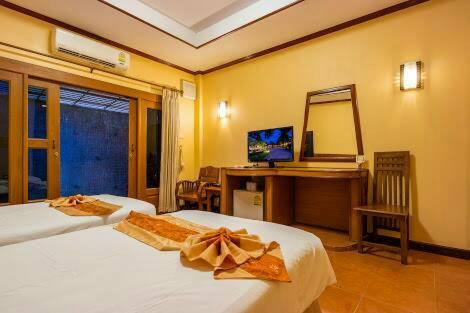1 dormitorio con 2 camas, escritorio y espejo en Baan Kiang Chan Resort, en Mae Sot