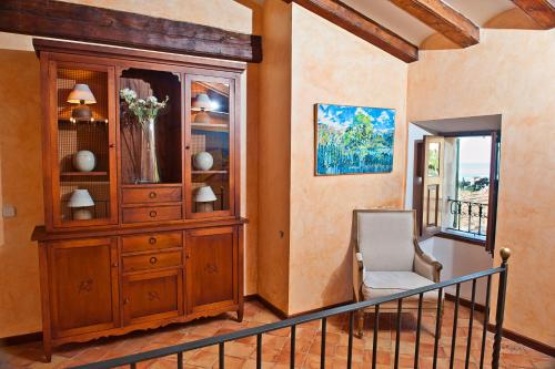 a living room with a wooden cabinet and a chair at Hotel y Apartamentos DES PUIG in Deia