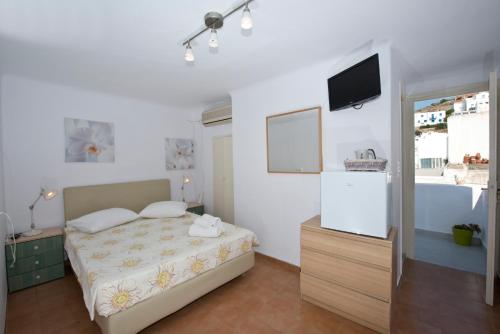 a bedroom with a bed and a flat screen tv at Karboni Hotel in Mýkonos City