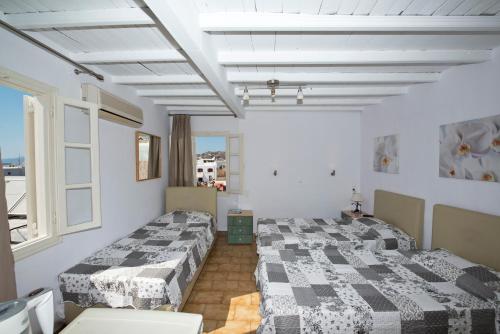 two beds in a room with white walls and windows at Karboni Hotel in Mýkonos City