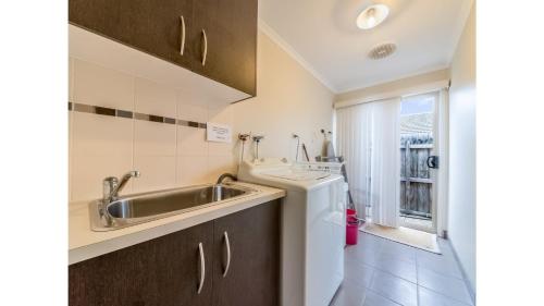 a small kitchen with a sink and a washing machine at A TOUCH OF CLASS - PET FRIENDLY (OUTSIDE ONLY) in Inverloch