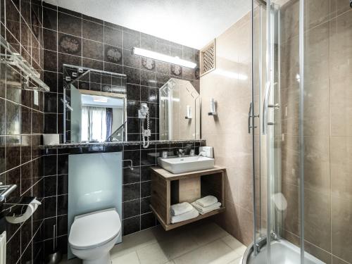 a bathroom with a toilet and a sink and a shower at Hotel Victoria in Maishofen