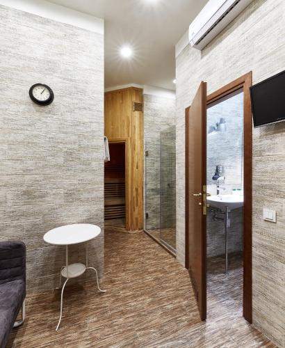 a bathroom with a sink and a table and a clock at Frapolli Hotel on Deribasivska street in Odesa