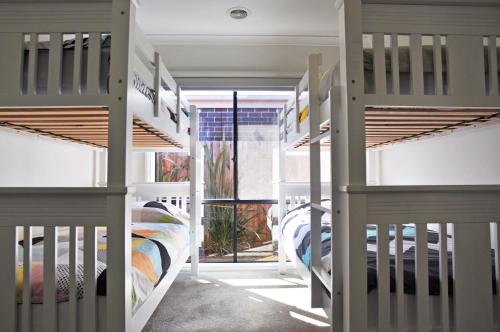 a group of bunk beds in a room with a window at Plovers Rest in Inverloch