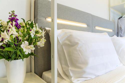 a vase of flowers on a table next to a bed at A&A Luxury Beach Villas in Nikiti