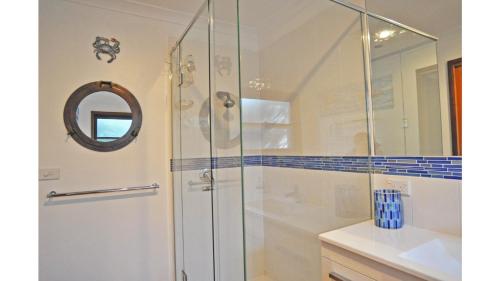 a bathroom with a shower with a mirror and a sink at SURF PLAZU - SURF SIDE in Inverloch