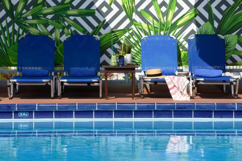 a pool with chairs and umbrellas in it at Poseidon Athens Hotel in Athens