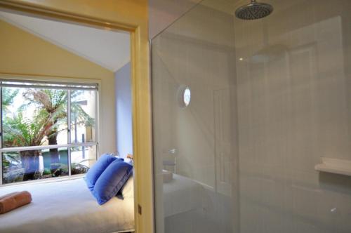 a bathroom with a shower and a bed and a window at THE SAILS 4 - CENTRAL LOCATION in Inverloch