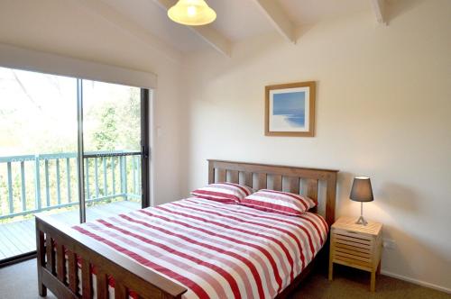 a bedroom with a bed and a large window at WAVELENGTH - WIFI & PET FRIENDLY (OUTSIDE ONLY) in Inverloch