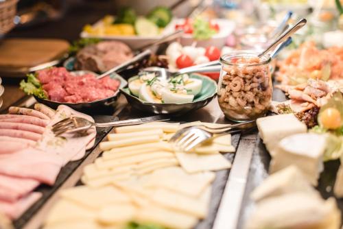 a buffet of food with cheese and meats and dips at Hotel Landhaus an de Dün in Sankt Peter-Ording