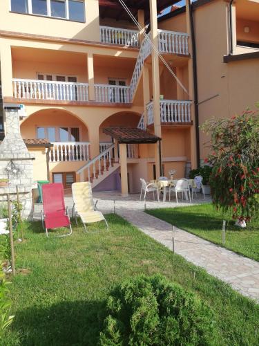 a building with chairs and tables in a yard at Apartment Zdravko in Štinjan