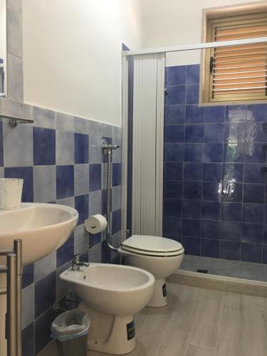 Baño de azulejos azules con aseo y lavamanos en Forte Village, en Marzamemi