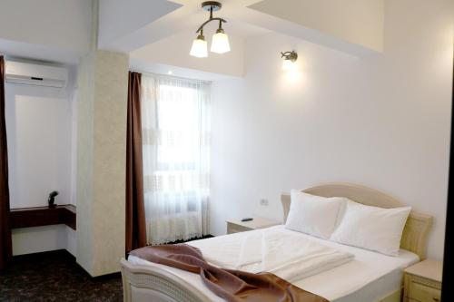a bedroom with a white bed and a window at Hotel Restaurant Imperial in Sighişoara