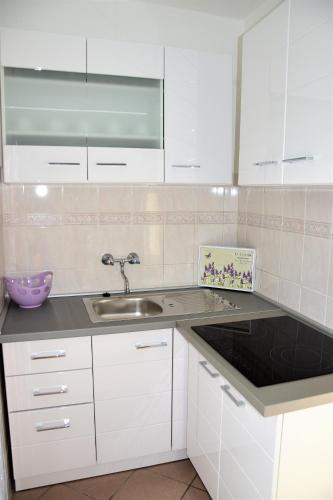 a kitchen with white cabinets and a sink at Apartmani Novosel in Šilo