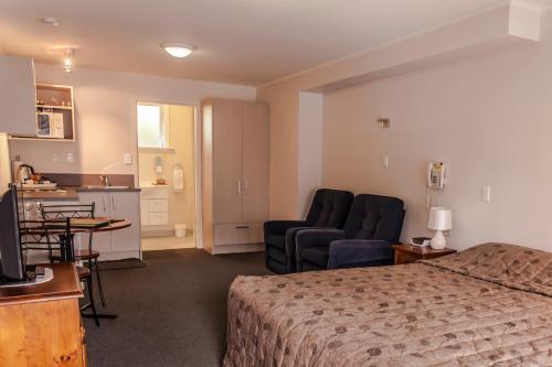 Habitación de hotel con cama, sofá y cocina en Ashleigh Court Motel en Christchurch