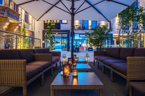 a restaurant with couches and tables and an umbrella at AKZENT Hotel Villa Saxer in Goslar