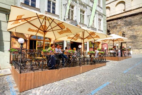 people sitting under umbrellas at an outdoor cafe at Golden Star in Prague