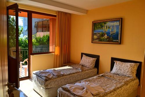 a room with two beds and a window with a view at Joro Guest House in Sveti Vlas