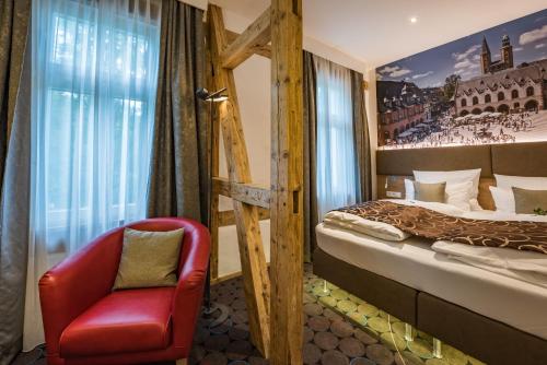 a hotel room with a bed and a red chair at AKZENT Hotel Villa Saxer in Goslar
