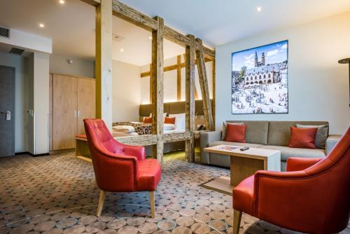 a living room with red chairs and a couch at AKZENT Hotel Villa Saxer in Goslar