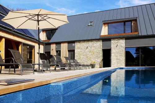 - une piscine avec des chaises et un parasol à côté d'une maison dans l'établissement SÖRWESPA Nature Resort, à Salme